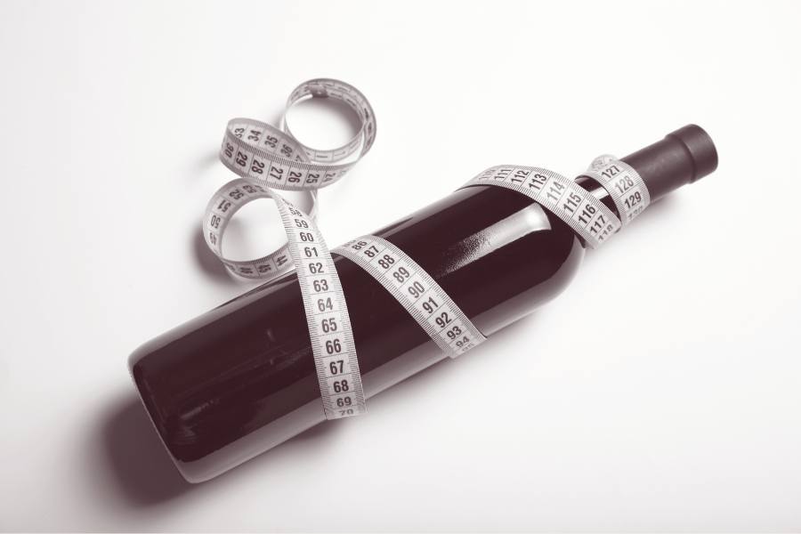 A wine bottle wrapped in measuring tape shows the concept of moderate alcohol intake