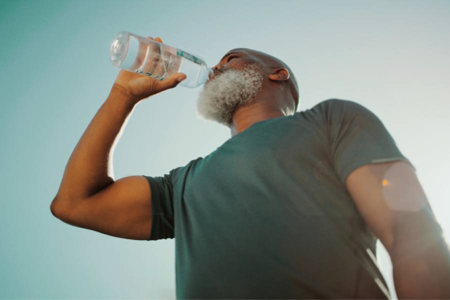 Proper hydration is essential: a concept pic shows a man drinking water while on a run