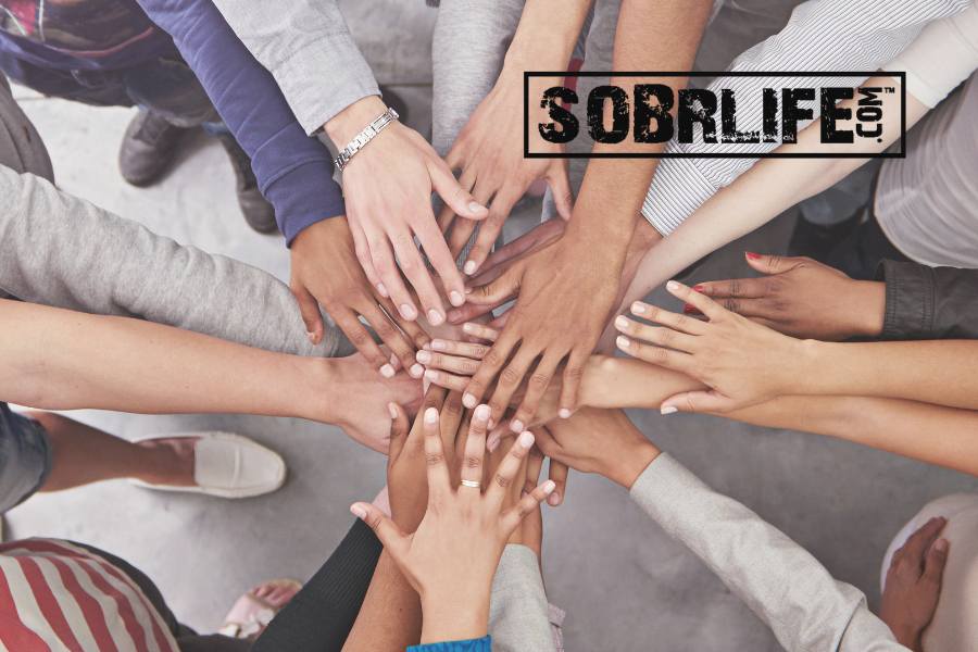 a group of people putting their hands together shows the concept of recovery for all as movement embraced at SOBRLIFE.com