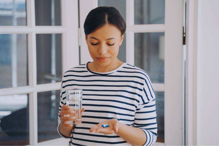 A woman considers When Substance Use or Abuse Becomes a Form of Self Soothing as she looks at pills in her hand