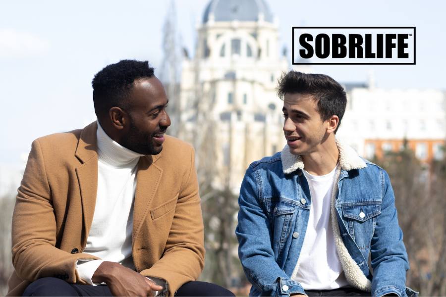 Two men talk on a bench to show the concept of how to become a sober companion