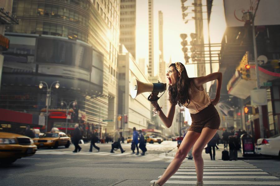 A woman with a megaphone in the street shows the concept of recovering out loud with SOBRLIFE