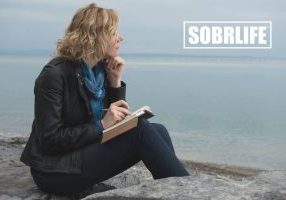 A woman stares out over the ocean with a pad of paper and pen to show the concept of addiction recovery poems