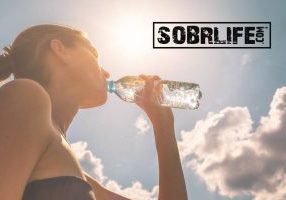 Drinking water in addiction recovery is essential: a woman drinking bottle SobrWater shows this concept